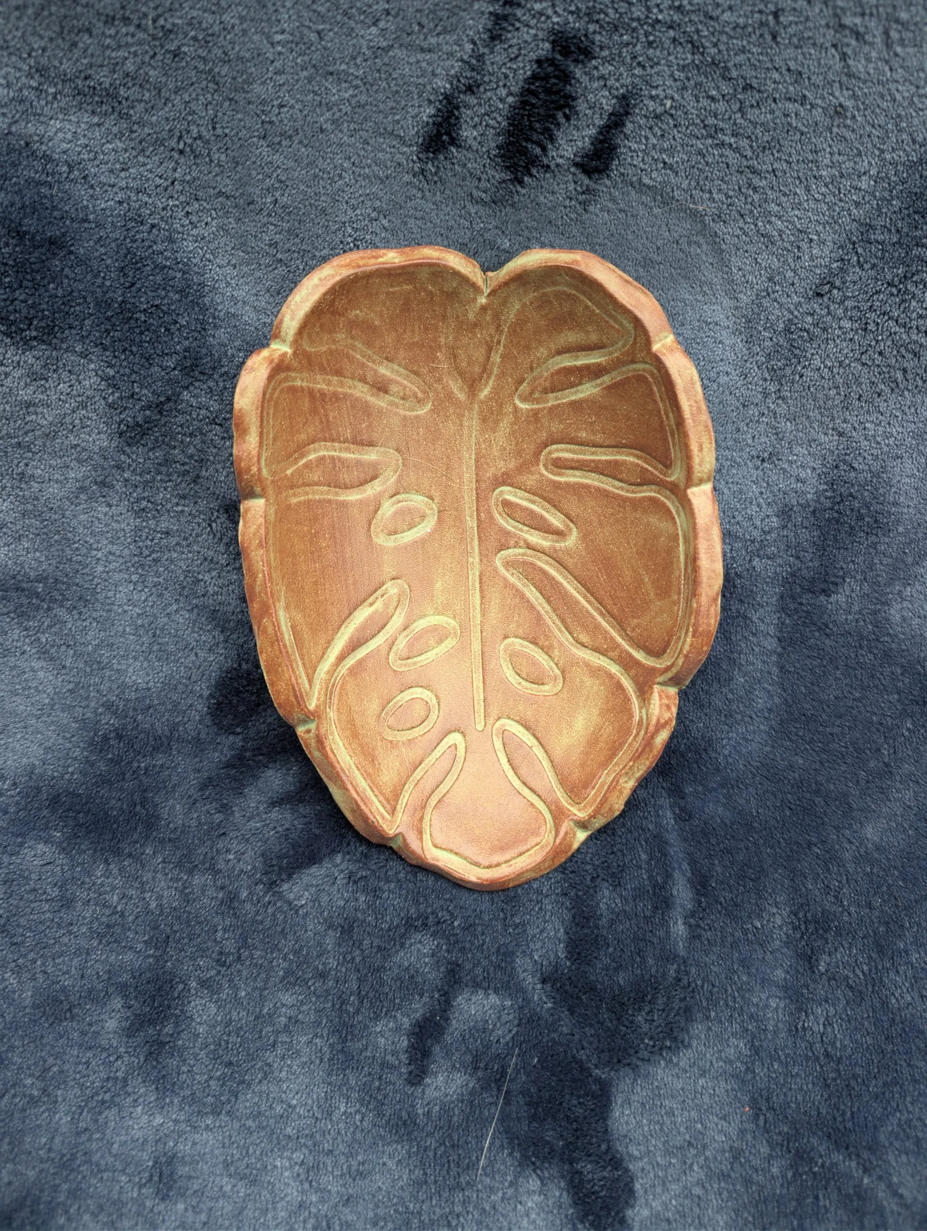 The same leaf plate under warmer light, where the green reads as tan and the rim as pale gold.